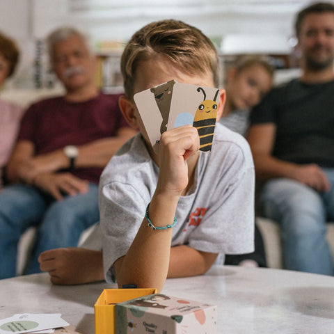 Junge liest eine Karte, im Hintergrund die Familie auf dem Sofa