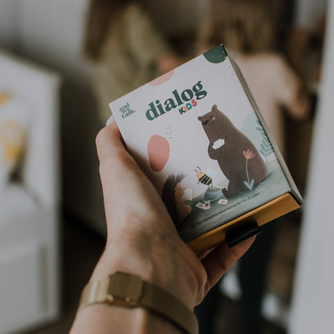 Hand hält die Schachtel von Dialog Kids
